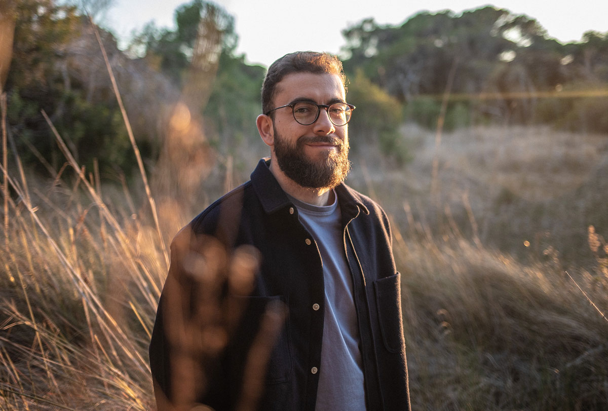 A portrait photo of the designer behind Pher website, Ivan Perez, in a field with trees in the background.